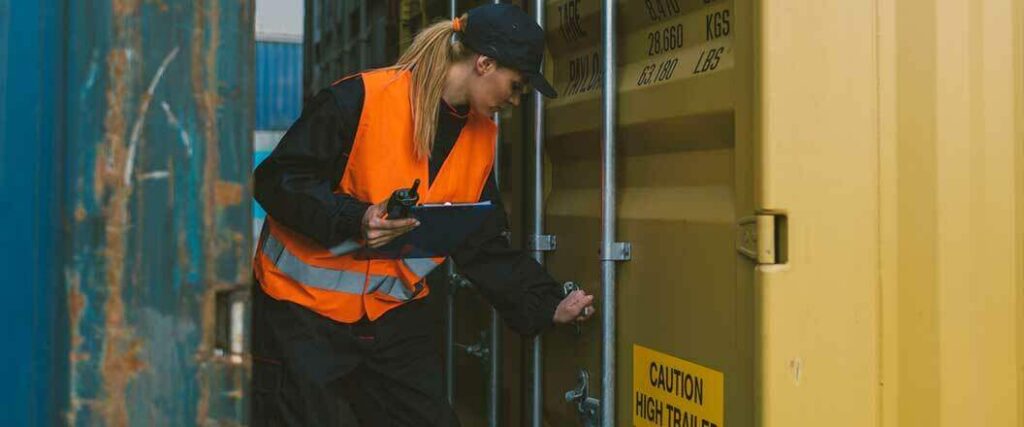 A warehouse employee inspecting the latch on a cargo container.