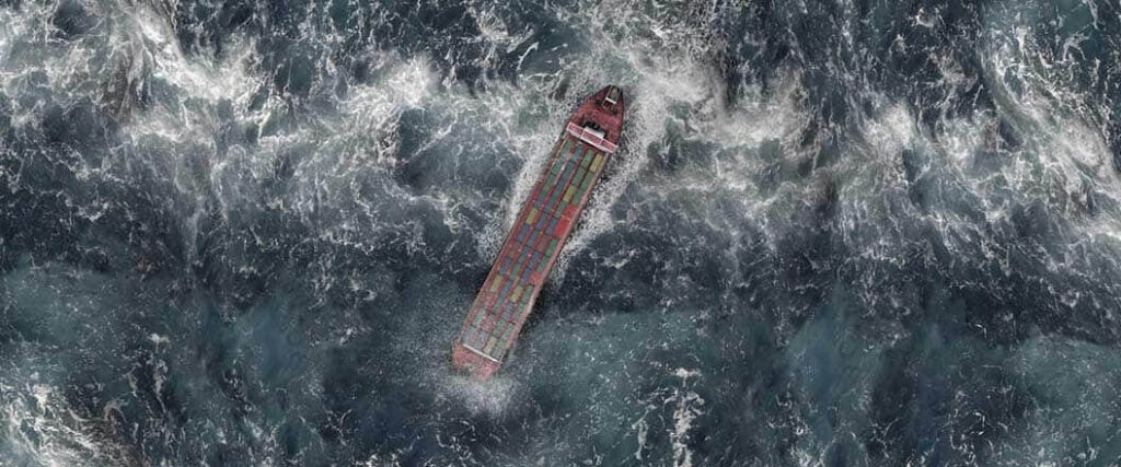 An overhead view of a cargo vessel in rough waters.