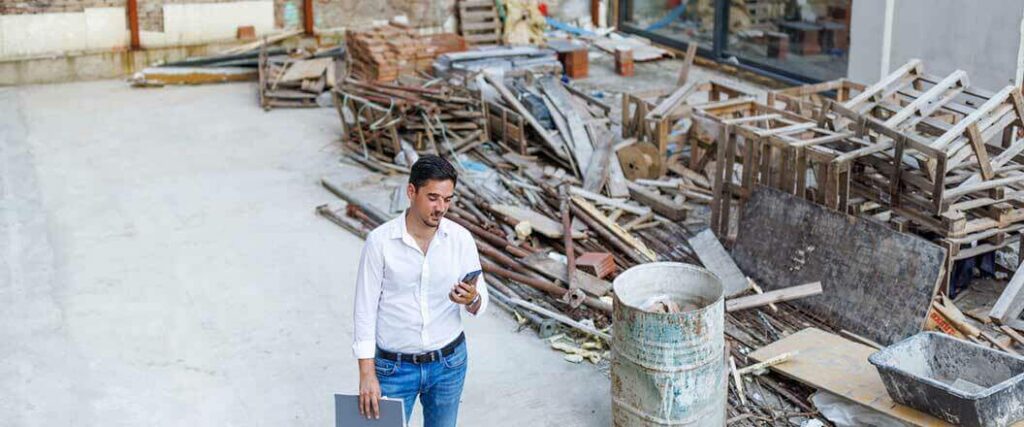 A man standing next to a pile of debris from a hurricane.